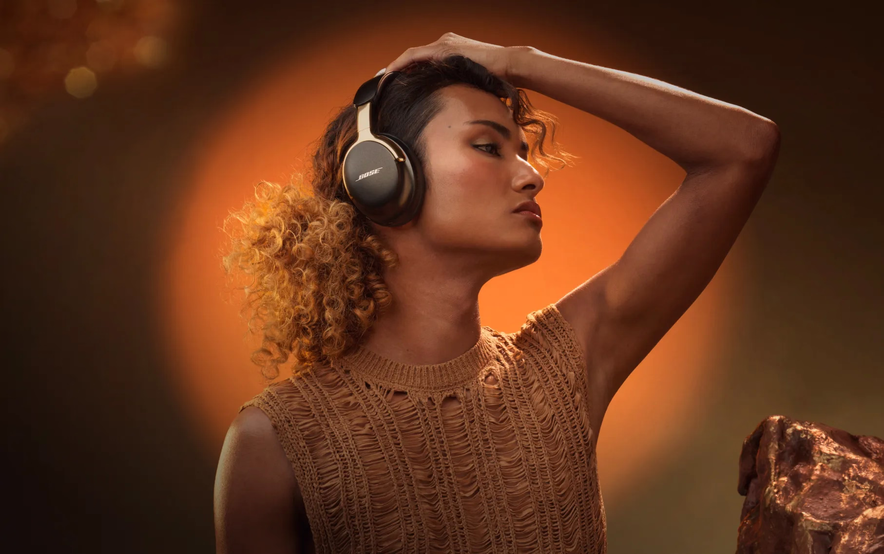 Woman wearing Bose QuietComfort Ultra Headphones (2nd Gen) in Desert Gold.